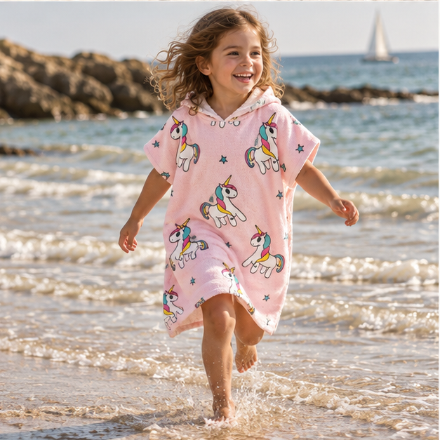 Poncho De Bain Licorne – Rose / Enfant, porté en mouvement au bord de l’océan
