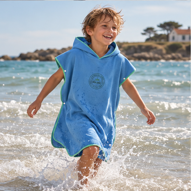 Poncho Microfibre Enfant – Bleu Clair / M, Bleu Clair / L, porté en mouvement au bord de l’océan