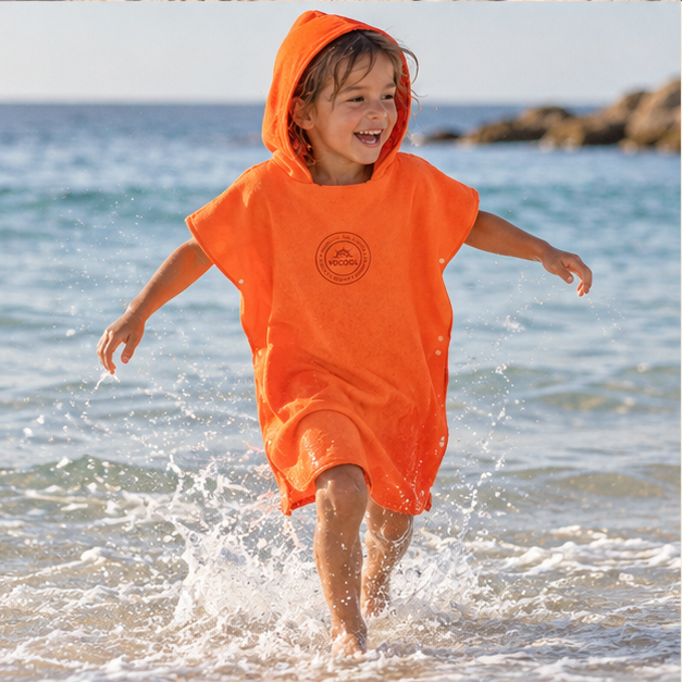 Poncho Microfibre Enfant – Orange / M, Orange / L, porté en mouvement au bord de l’océan