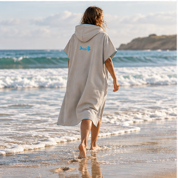 Poncho Microfibre Gris – Gris / Adulte, porté en mouvement au bord de l’océan