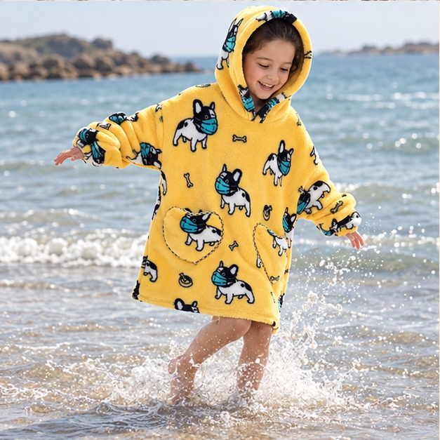 Poncho Plaid Bouledogue – Jaune / Enfant, porté en mouvement au bord de l’océan