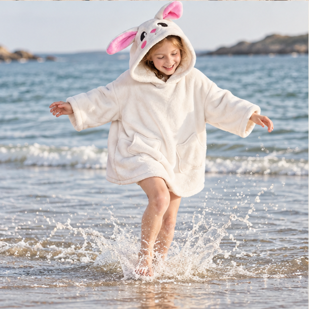 Poncho Plaid Lapin – Blanc / Enfant, porté en mouvement au bord de l’océan