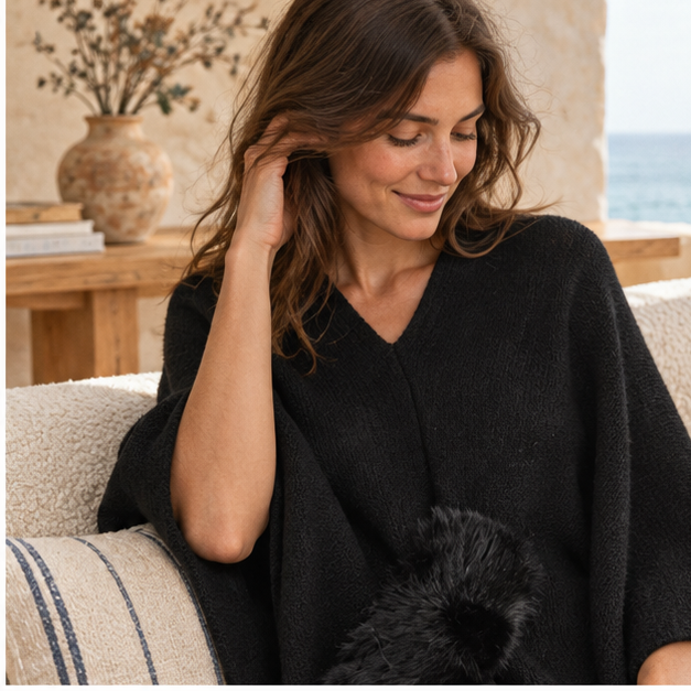 Pull Poncho Pompon – Noir / Adulte, dans un intérieur côtier lumineux